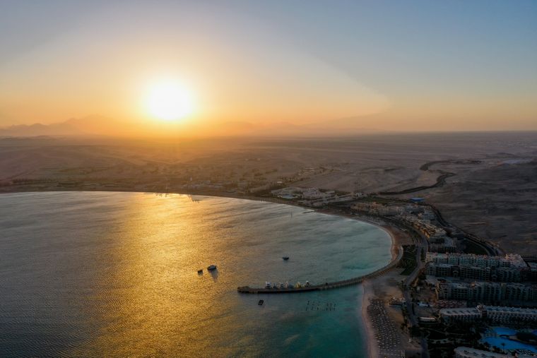 Aerial view of a curved bay on the Hurghada coast as the sun sets over the desert mountains